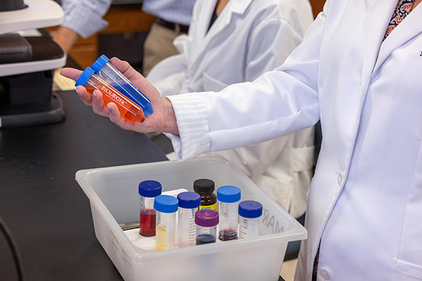 Researcher in lab coat holding vials